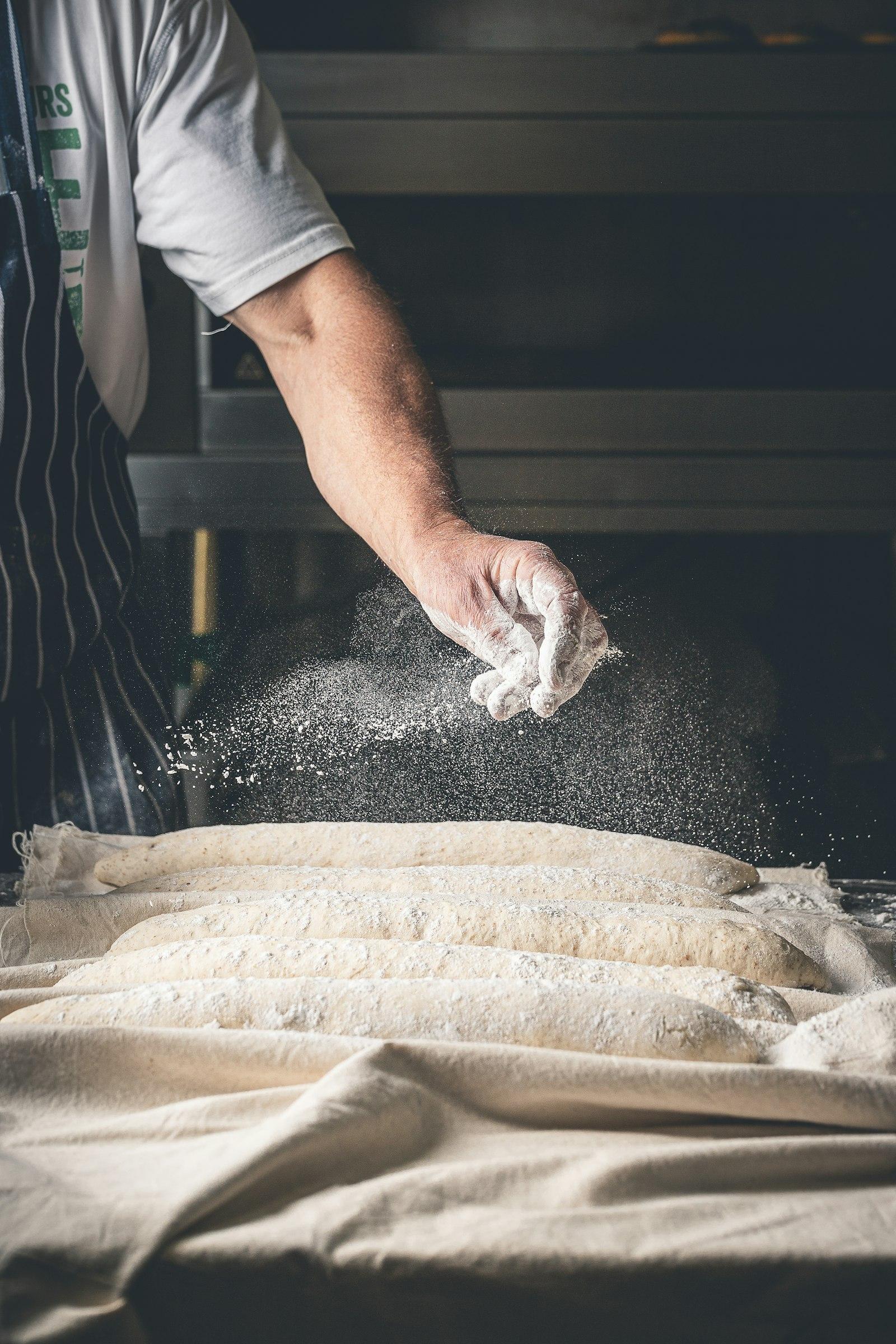 Chef menaburkan tepung di meja kerja bakery komersial