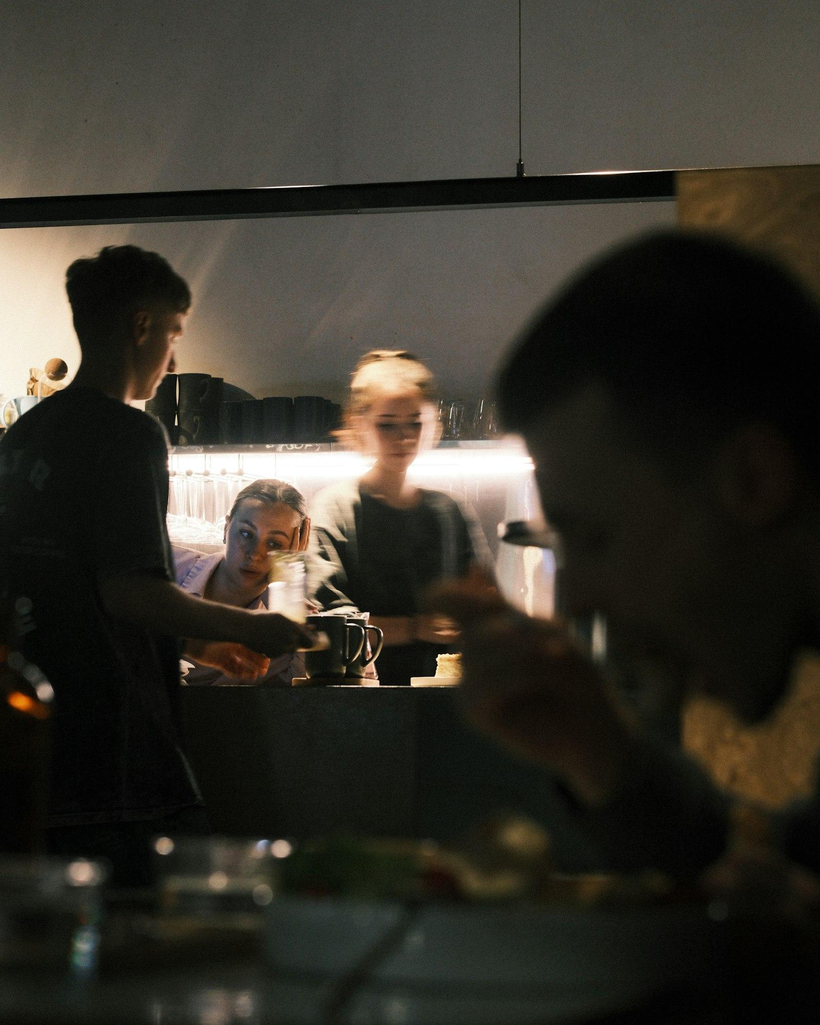 Tamu dan staf di restoran hotel dengan pencahayaan hangat saat malam